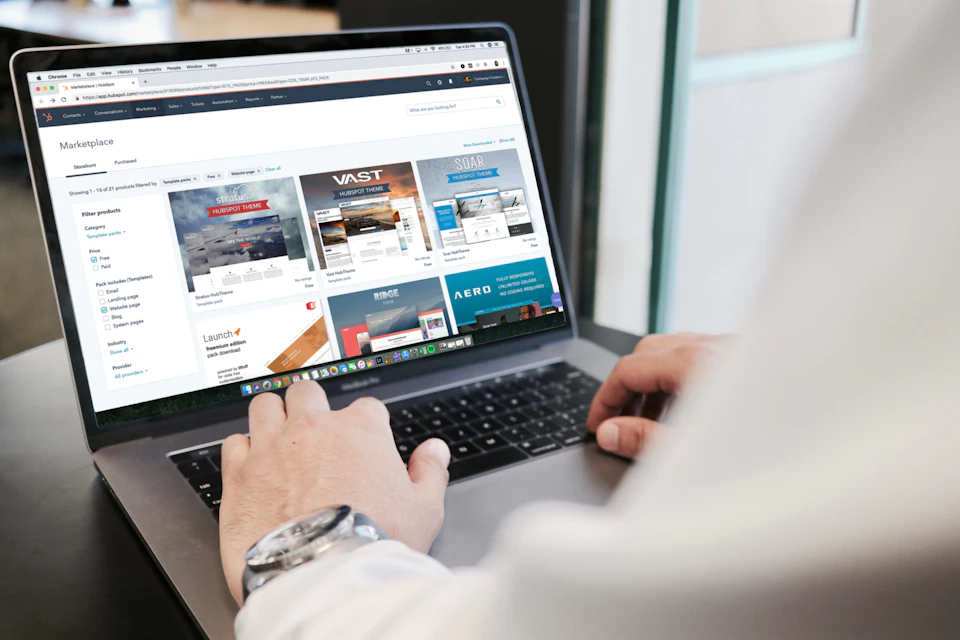 Manios sobru un portátil cun una páxina web n’escran